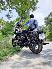 Rear view of man riding motorcycle on road against sky