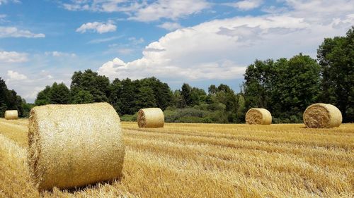 Hay bales on field against sky