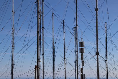 Low angle view of electricity pylon against blue sky