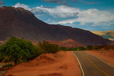 Road leading towards mountains against sky