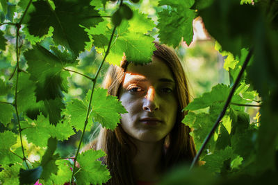 Portrait of young woman standing amidst plants