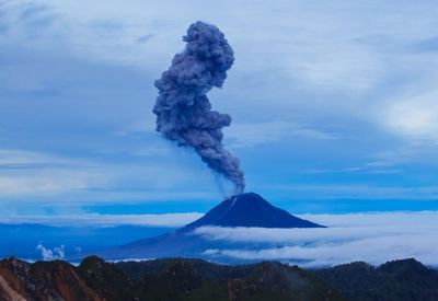 Smoke emitting from volcanic mountain against sky