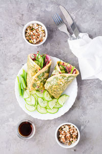 Egg rolls filled with pastrami, vegetables and green onions on a plate, sprouted grains 