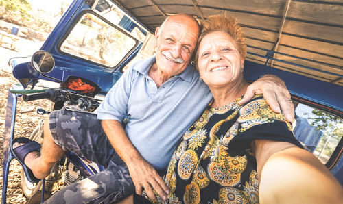 Portrait of smiling couple sitting on vehicle