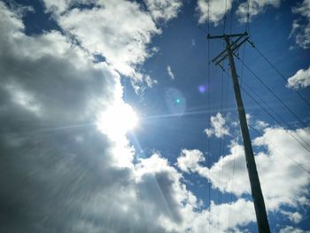 Low angle view of electric pole against bright sky