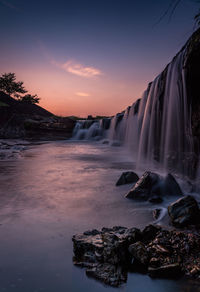 Scenic view of waterfall against sky during sunset