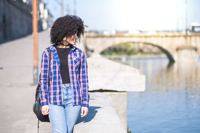 Woman looking at lake while walking on bridge in city