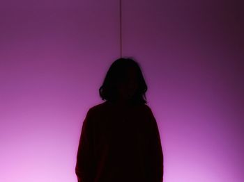 Silhouette woman standing against pink wall