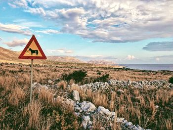 Road sign on landscape against sky