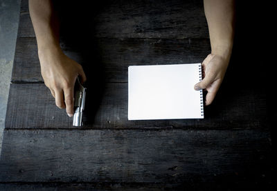 Midsection of woman holding paper on table