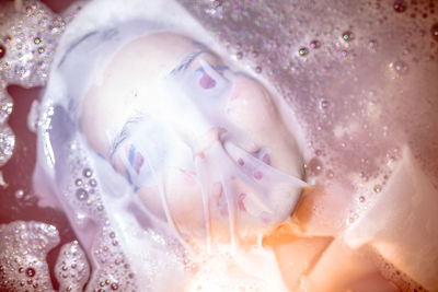 Close-up of young woman with face covered by textile in bathtub