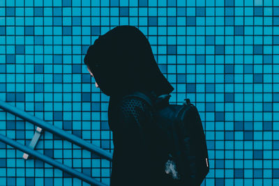 Low angle view of woman against blue tiled wall