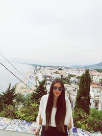 Portrait of young woman against sky