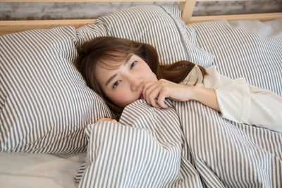 Portrait of young woman lying on bed