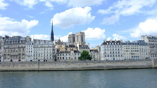 Seine river against notre dame de paris amidst buildings in city