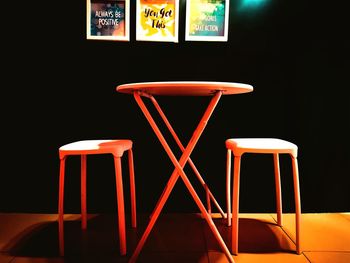 Close-up of empty chairs and table against black background