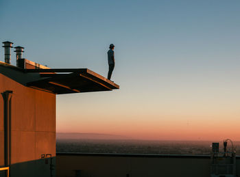 Man standing by sea against clear sky during sunset