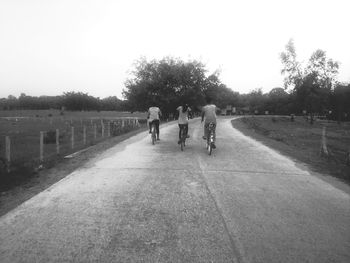 Rear view of people walking on road against sky