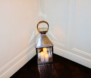 Illuminated lamp on table against wall at home