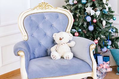 Teddy bear on seat by christmas tree at home