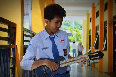 Young man playing guitar in corridor