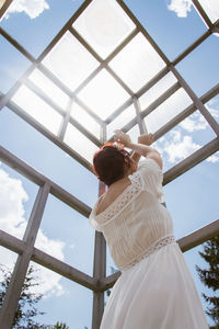 Low angle view of woman standing against sky