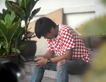 Man using smart phone sitting on steps outdoors