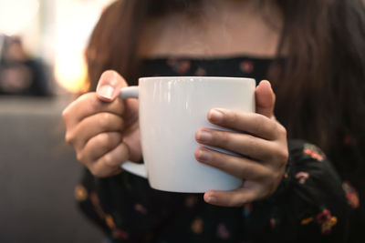 Midsection of woman holding coffee cup outdoors