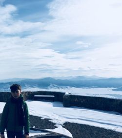 Portrait of boy standing on snow covered mountain against sky