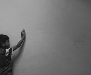 Boy holding asthma inhaler against wall