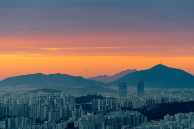Aerial view of buildings in city against romantic sky at sunset