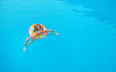 High angle view of girl swimming with inflatable ring in pool