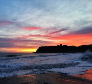 Scenic view of sea against dramatic sky during sunset