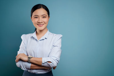 Portrait of a smiling young woman against blue background