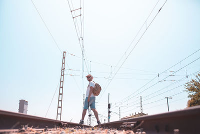 Low angle view of man standing on railroad track against sky