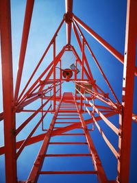 Low angle view of child on playground against clear blue sky