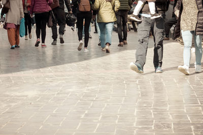 Low section of people walking on street in city