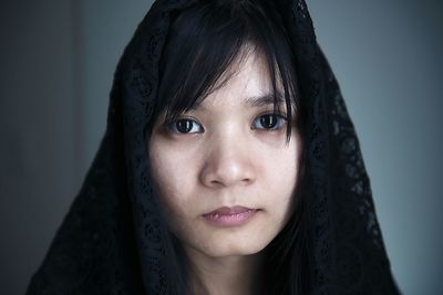 Close-up portrait of young woman wearing scarf standing against wall