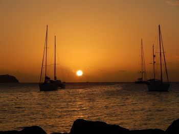 Silhouette of sailboats in sea during sunset