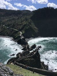 Scenic view of rocky shore by sea against sky