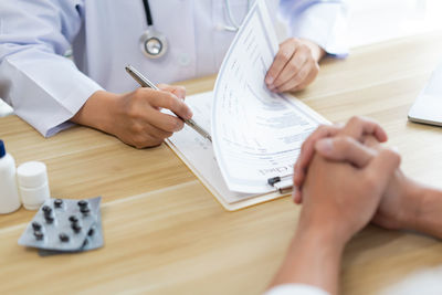 Midsection of doctor giving medicine to client in office