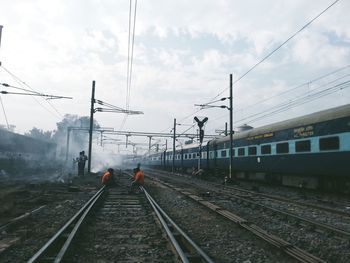 Men repairing railroad tracks against sky