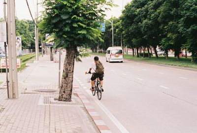 Rear view of man riding bicycle on road