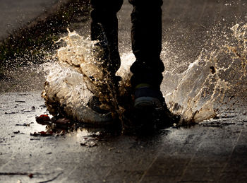 Low section of person splashing on puddle