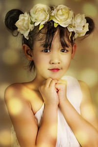 Portrait of girl wearing flowers against wall