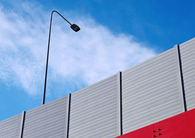 A red and gray steel highway lamppost on the overpass