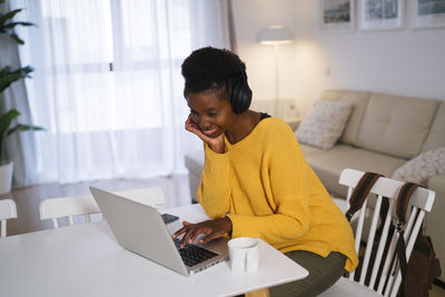 Young woman using mobile phone while sitting on table