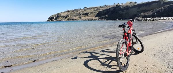 Bicycle on beach by sea against sky