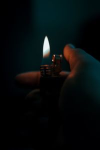 Close-up of hand holding candle against black background