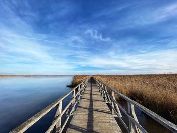 Boardwalk on field against sky